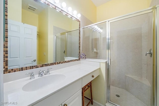 bathroom featuring a shower with shower door and vanity