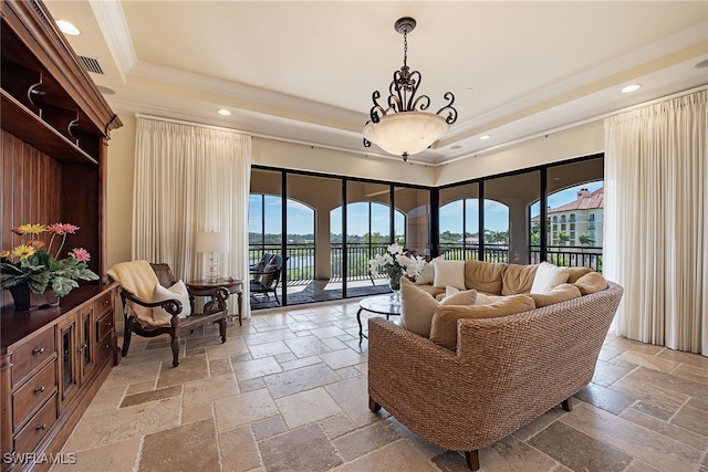 living room with a notable chandelier, a healthy amount of sunlight, a tray ceiling, and crown molding