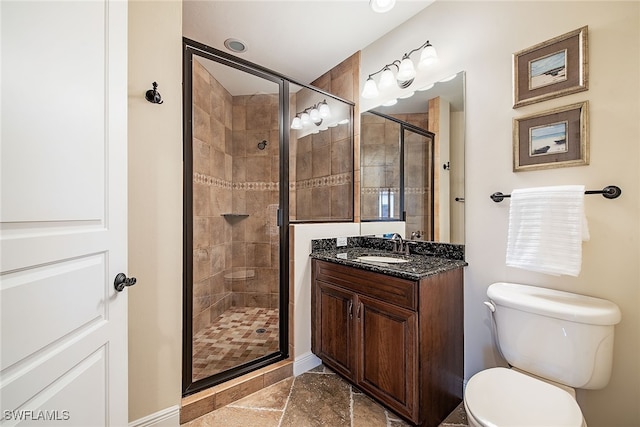 bathroom featuring toilet, a shower with shower door, and vanity