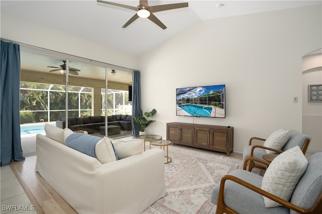 living room featuring ceiling fan, lofted ceiling, and light wood-type flooring