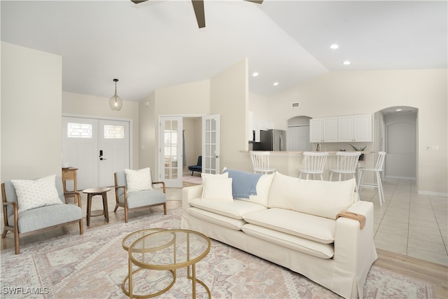 living room with french doors, light hardwood / wood-style floors, high vaulted ceiling, and ceiling fan