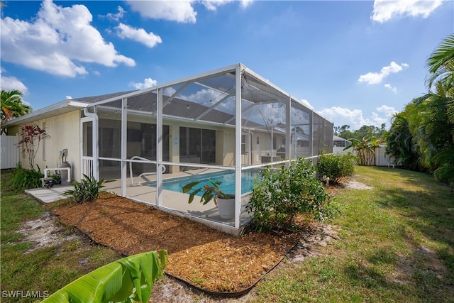 rear view of property with a yard, a patio, and a lanai