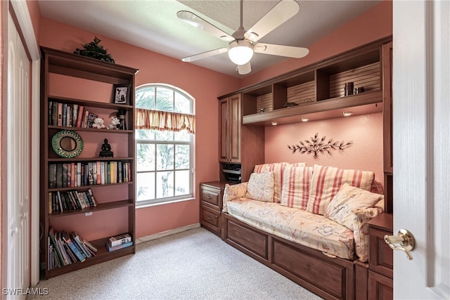 living area featuring a textured ceiling, light colored carpet, and ceiling fan