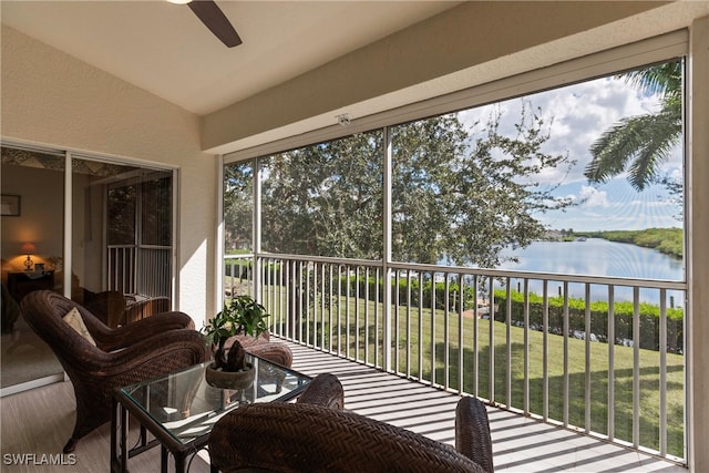 sunroom featuring lofted ceiling, ceiling fan, a water view, and plenty of natural light