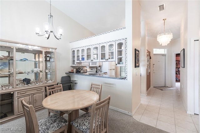 dining space with light tile patterned flooring, a notable chandelier, and high vaulted ceiling