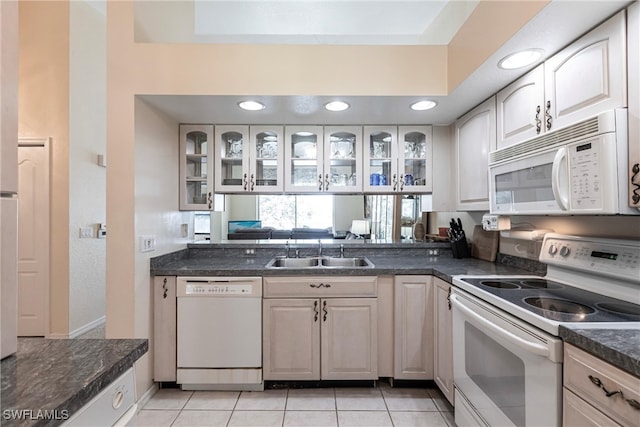 kitchen with white cabinetry, sink, light tile patterned floors, and white appliances