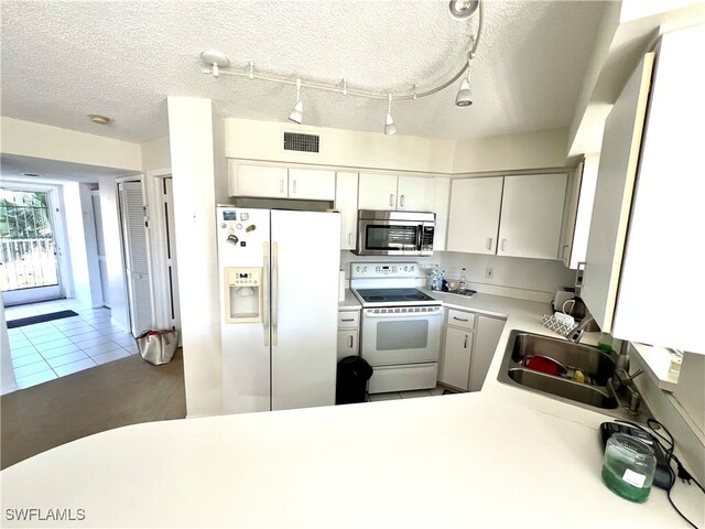 kitchen with tile patterned floors, sink, a textured ceiling, and white appliances