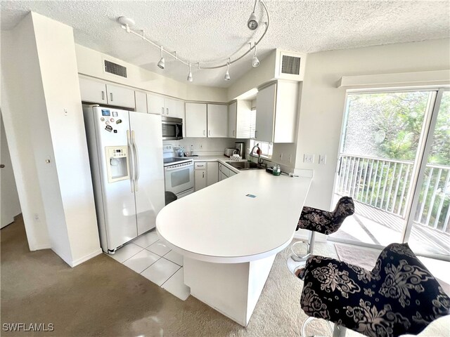 kitchen featuring white appliances, sink, a textured ceiling, kitchen peninsula, and white cabinets