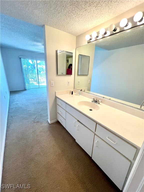 bathroom with vanity, baseboards, and a textured ceiling