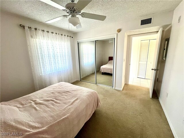 bedroom with light carpet, a closet, a textured ceiling, and ceiling fan