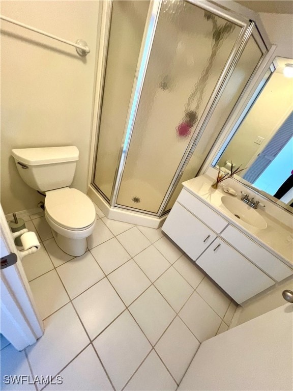 bathroom featuring vanity, tile patterned flooring, toilet, and an enclosed shower