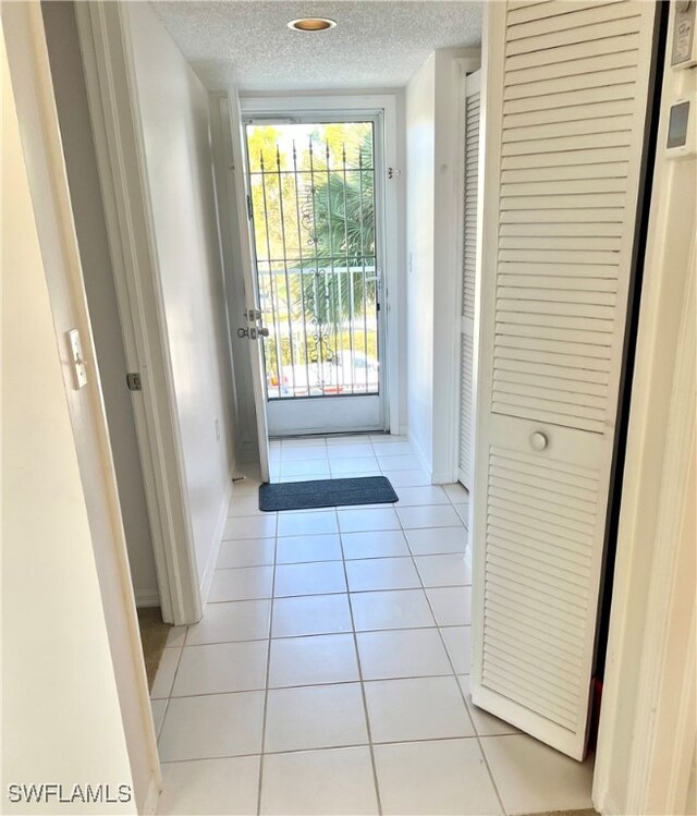 entryway with light tile patterned flooring, a textured ceiling, and baseboards