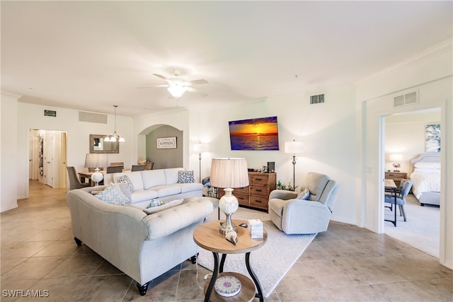 tiled living room featuring crown molding and ceiling fan with notable chandelier