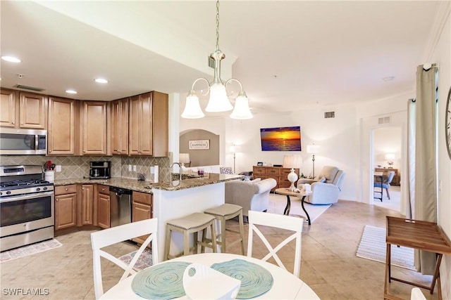 3157 Aviamar Cir Unit 102, Naples, FL 34114 - kitchen featuring appliances with stainless steel finishes, tasteful backsplash, light stone counters, open floor plan, and light tile patterned floors