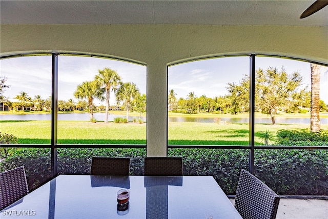 unfurnished sunroom with a water view and ceiling fan