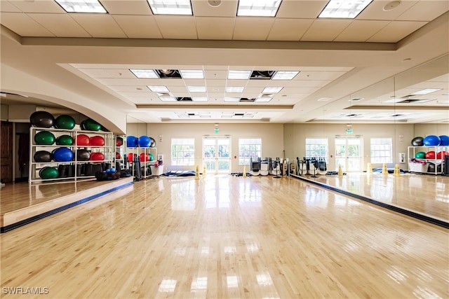 workout area with a paneled ceiling and hardwood / wood-style floors