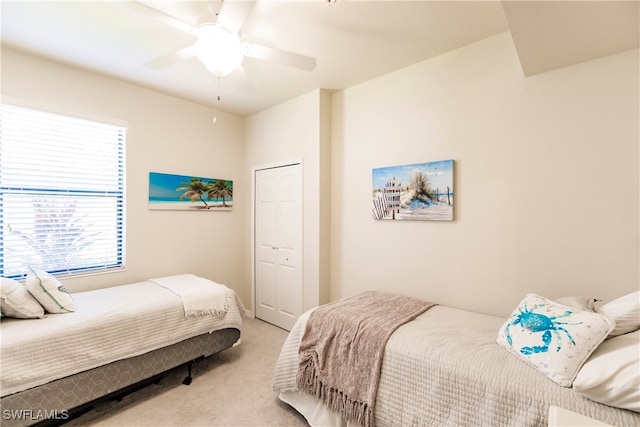 bedroom with a closet, ceiling fan, and light colored carpet