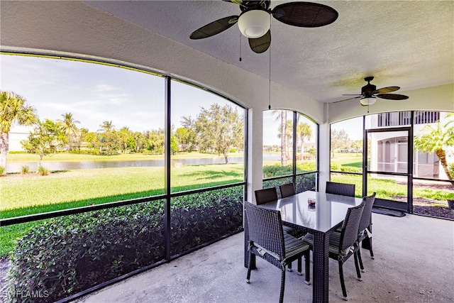 sunroom / solarium featuring a water view and ceiling fan