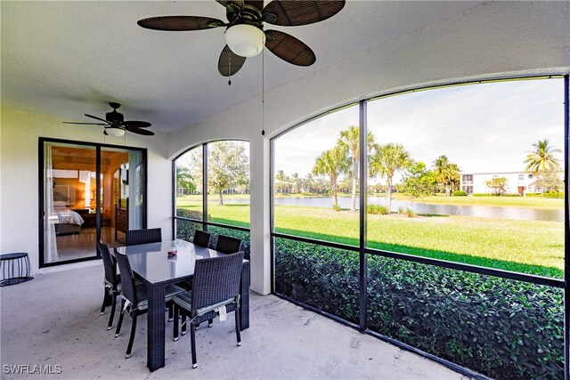 sunroom / solarium with a water view and ceiling fan