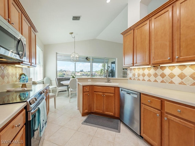 kitchen with tasteful backsplash, appliances with stainless steel finishes, sink, hanging light fixtures, and vaulted ceiling