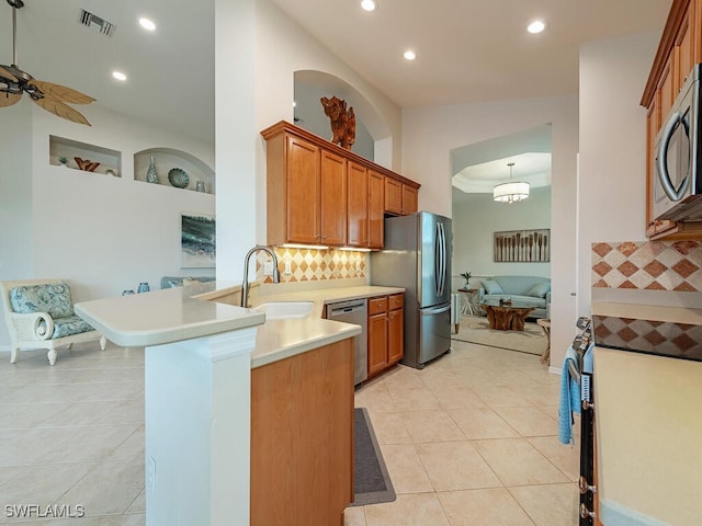 kitchen featuring kitchen peninsula, backsplash, appliances with stainless steel finishes, light tile patterned flooring, and sink