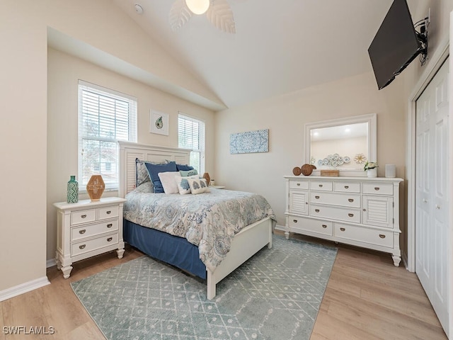 bedroom featuring a closet, light hardwood / wood-style floors, vaulted ceiling, and ceiling fan