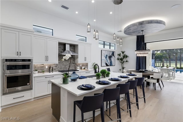 kitchen featuring a healthy amount of sunlight, stainless steel double oven, and hanging light fixtures