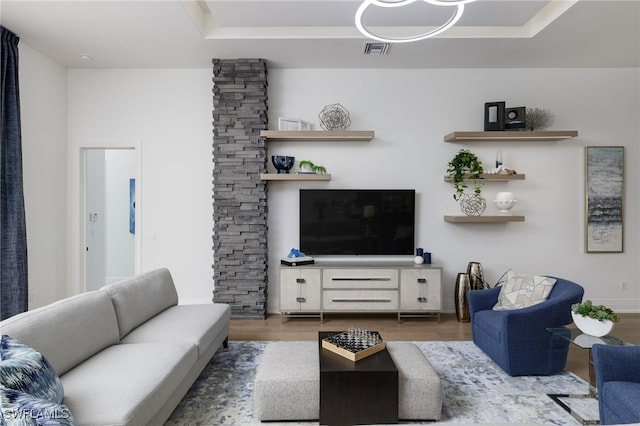 living room featuring wood-type flooring and a tray ceiling