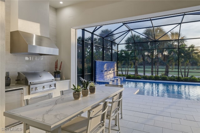 view of swimming pool featuring a patio, grilling area, glass enclosure, and exterior kitchen