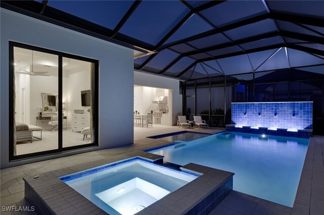 view of pool featuring exterior kitchen, a pool with connected hot tub, a lanai, and a patio
