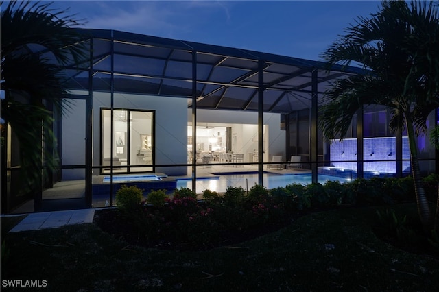 rear view of property with a patio, a pool with hot tub, and glass enclosure