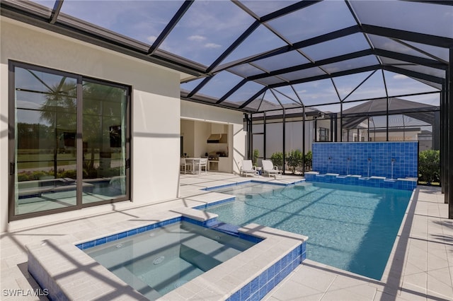 view of swimming pool with glass enclosure, a patio area, and a pool with connected hot tub