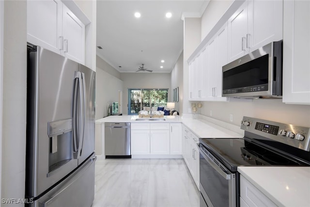 kitchen featuring kitchen peninsula, white cabinets, ceiling fan, crown molding, and stainless steel appliances