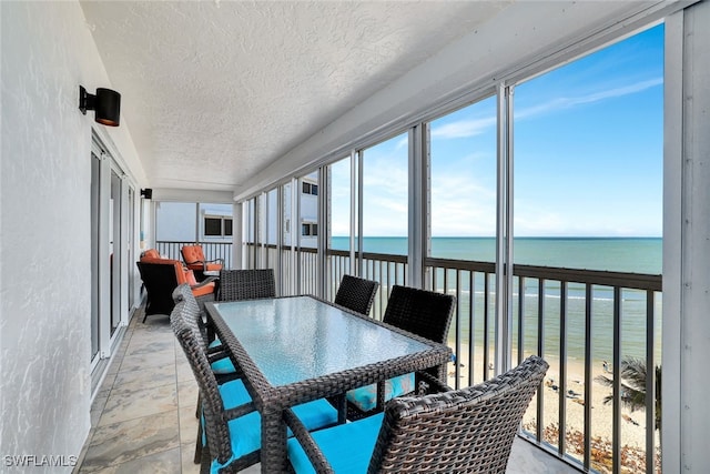 sunroom featuring a water view