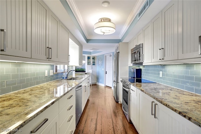 kitchen featuring light stone countertops, stainless steel appliances, crown molding, dark wood-type flooring, and white cabinets