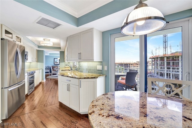 kitchen featuring light stone countertops, tasteful backsplash, stainless steel appliances, decorative light fixtures, and white cabinets