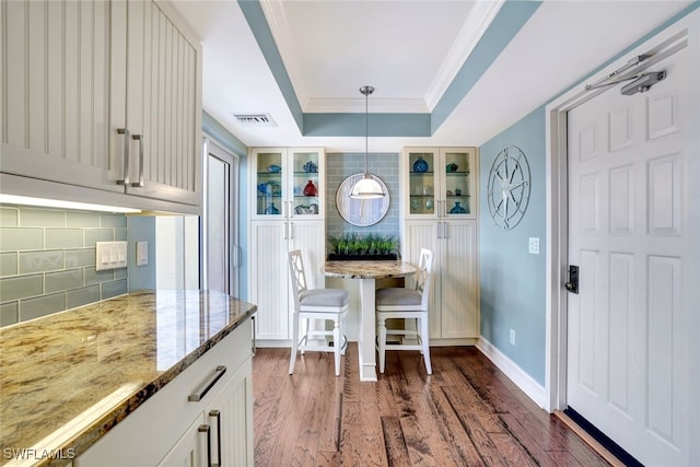 dining space with dark hardwood / wood-style flooring, crown molding, and a tray ceiling