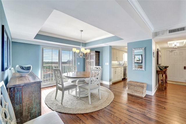 dining room featuring wood-type flooring, a tray ceiling, crown molding, and a notable chandelier