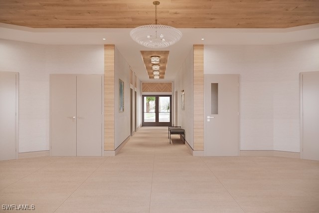 hallway with french doors, light tile patterned floors, a towering ceiling, a notable chandelier, and wood ceiling