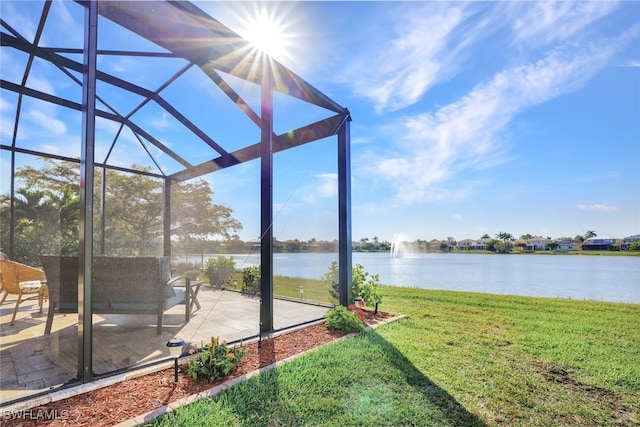 view of yard with glass enclosure, a water view, and a patio