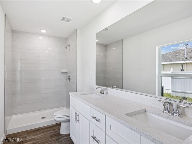 bathroom featuring vanity, hardwood / wood-style floors, a tile shower, and toilet