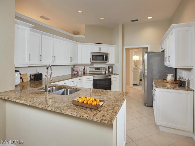 kitchen with white cabinets, sink, light stone countertops, kitchen peninsula, and stainless steel appliances