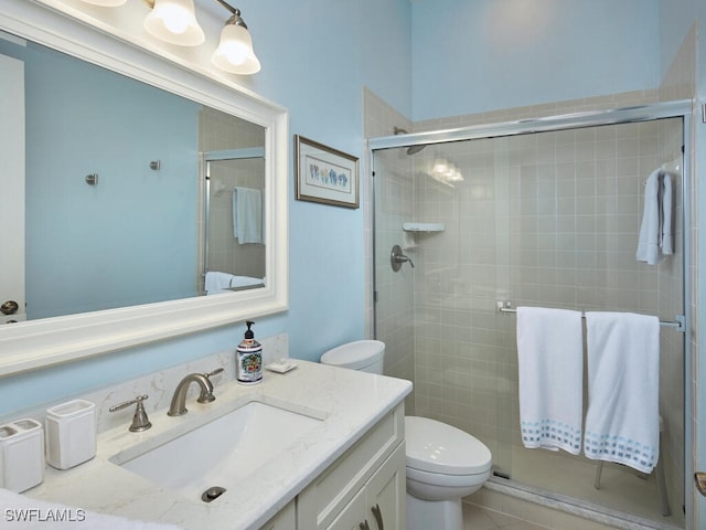 bathroom featuring tile patterned floors, vanity, toilet, and a shower with shower door