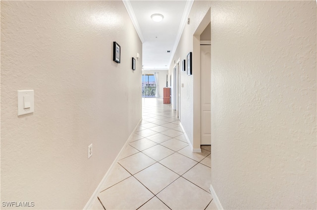 corridor featuring light tile patterned floors, ornamental molding, and a textured wall