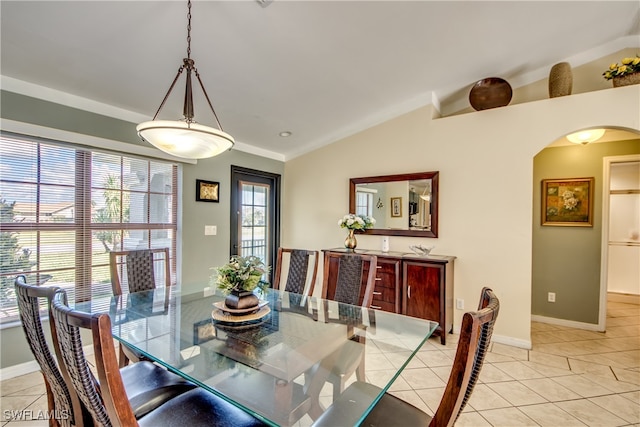 tiled dining room featuring vaulted ceiling and crown molding