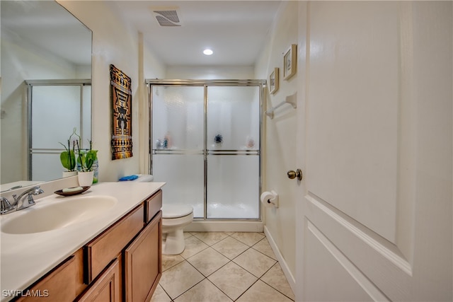 bathroom featuring tile patterned floors, a shower with door, vanity, and toilet