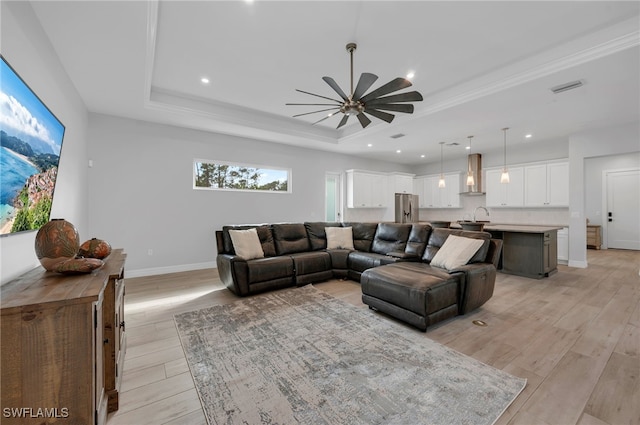 living room featuring ceiling fan, a raised ceiling, sink, and light hardwood / wood-style flooring