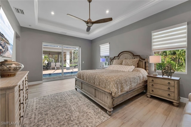 bedroom with ceiling fan, light hardwood / wood-style flooring, access to outside, and a tray ceiling