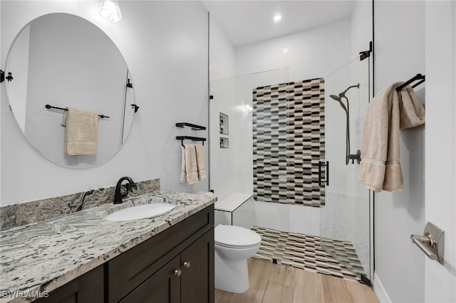 bathroom with wood-type flooring, vanity, toilet, and a shower with door