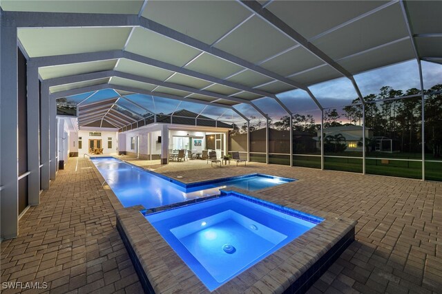 pool with an in ground hot tub, a patio area, and glass enclosure